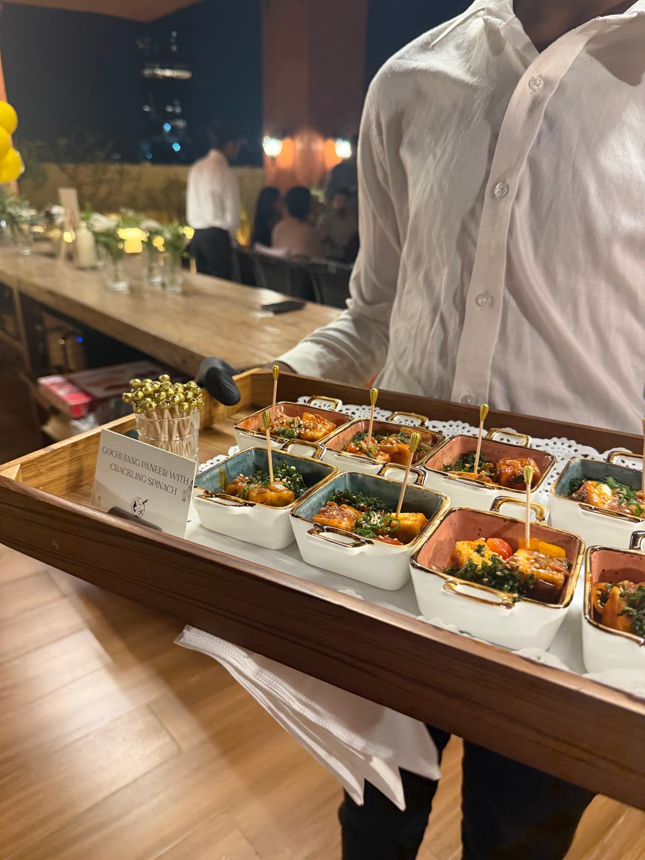 Server presenting gochujang cottage cheese with crackling spinach in mini ramekins