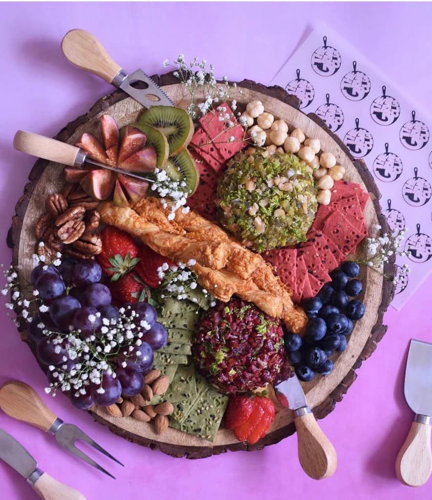 Gourmet cheese wheels with crackers, berries and nuts on a wooden board